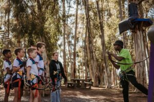 School learners at Acrobranch listening attentively to an instructor during the safety briefing before their treetop adventure